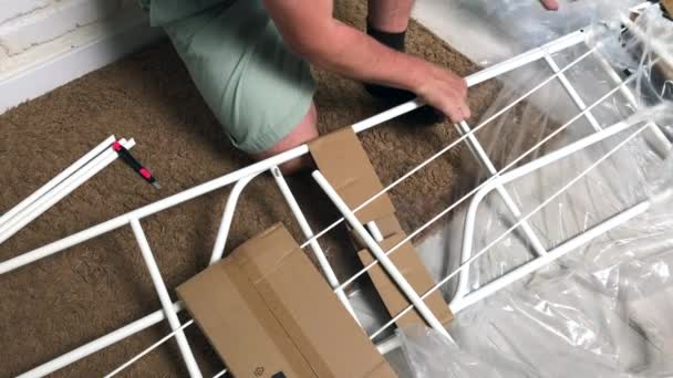 The man is squatting, unpacking the rack. She cuts the film and packaging with a knife. Household chores during self-isolation — Stock Video