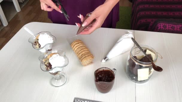 A mulher decora a sobremesa com um toque de chocolate. Faz uma sobremesa com biscoitos, chocolate e creme. — Vídeo de Stock