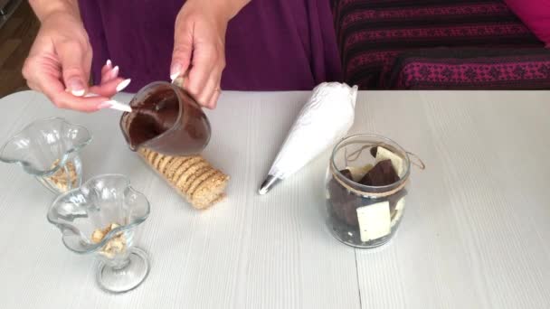Uma mulher adiciona chocolate a um biscoito. Faz sobremesa com biscoitos, chocolate e creme. — Vídeo de Stock