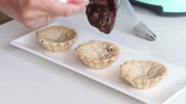 Bir kadın bisküviye sıvı çikolata koyar. Bir sepet pasta hazırlıyor. Yakın çekim.