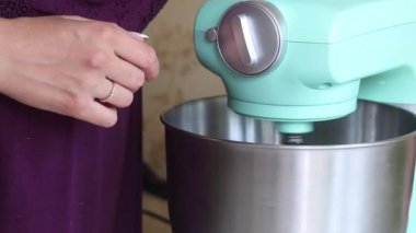 Kadın malzemeleri gezegen mikserine koyuyor. Tatlı kreması yapıyor. Yakın çekim..