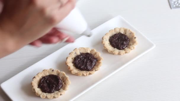 Uma mulher põe creme num brownie de chocolate. Uma cesta está preparando um bolo. Imagem de close-up — Vídeo de Stock