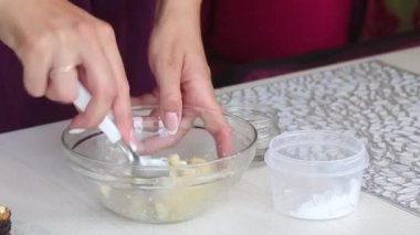 Bir kadın badem ezmesinden şeker yapar. Badem unu ve krema şekerini suyla karıştırıyor. Yakın çekim.