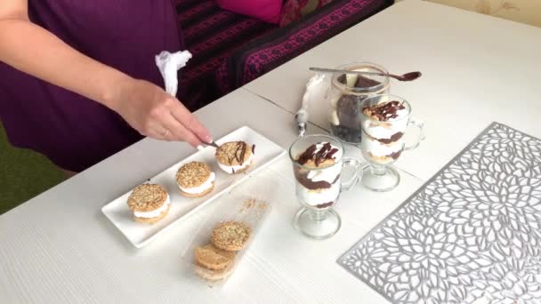 Egy nő sütit, csokit és tejszínt csinál. Csokival díszíti.. — Stock videók