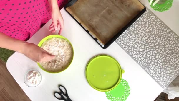 Una mujer prepara una masa para el pan de centeno. Amasa la masa en un recipiente, espolvoreándola periódicamente con harina. Filmado desde arriba — Vídeos de Stock