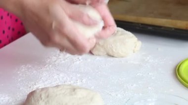 Kadın hamur toplarıyla çalışıyor. Ekmek için kuru sıkı yapar. Kurusıkı mermiler masanın üstünde. Yakın çekim..