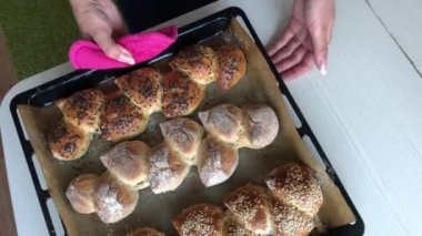 Bir kadın taze pişmiş çavdar ekmeğini masaya koyar. Susam tohumlu çivili ekmek. Yukarıdan çekilen.