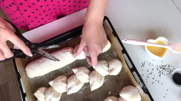 Una mujer prepara pan de centeno. Corta las piezas de trabajo con tijeras y moldea el pan en una espiga. Filmado desde arriba.. — Vídeos de Stock