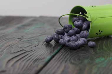 Metal kovada yabanmersini. Kova ters dönmüş, böğürtlenler dağılmış. Çam ağacından yapılmış. Yakın çekim..