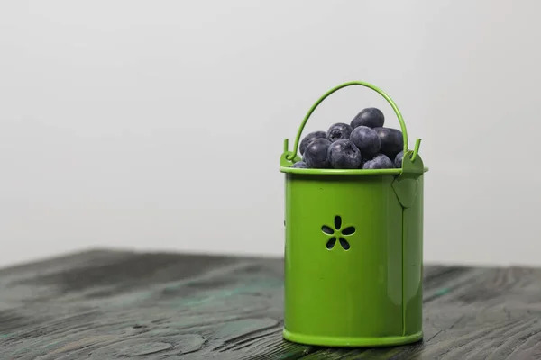 Blueberries in a metal bucket. On pine boards. Close-up shot.