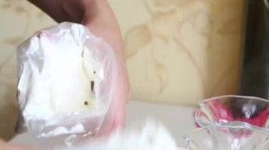 Bir kadın konteynırdan krem şanti alıp bir pasta torbasına koyar. Tatlı için krema hazırlıyor. Yakın çekim.