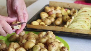 Kadın patatesleri doğrar ve onları bir yemek tepsisine koyar. Üzerinde kabak dilimleri ve fırında salamura var. Yakın çekim..