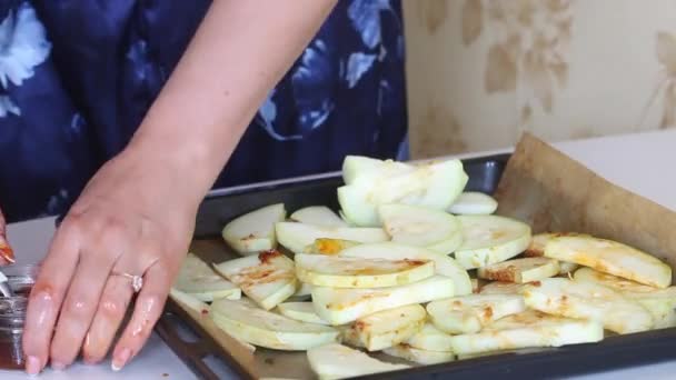 一个女人在切碎的西葫芦里加了大蒜和橄榄油。在烘烤单上，切碎的拉链，用于烘烤 — 图库视频影像