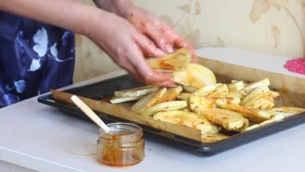 Een vrouw mengt gehakte courgettes met een marinade van knoflook en olijfolie. De groenten liggen op een bakplaat.. — Stockvideo