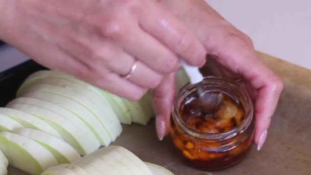 一个女人把切碎的大蒜和橄榄油混合在一起.烤盘上的旁边是切碎的苏其尼，用于烘焙。特写镜头. — 图库视频影像