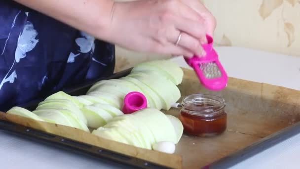 Женщина режет чеснок и добавляет его в оливковое масло. Рядом, на подносе, нарезанные цуккини для выпечки. Крупный план. — стоковое видео