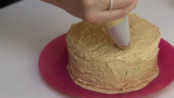 Worteltaart bakken. De vrouw versiert de taart met room. Close-up opname. — Stockvideo