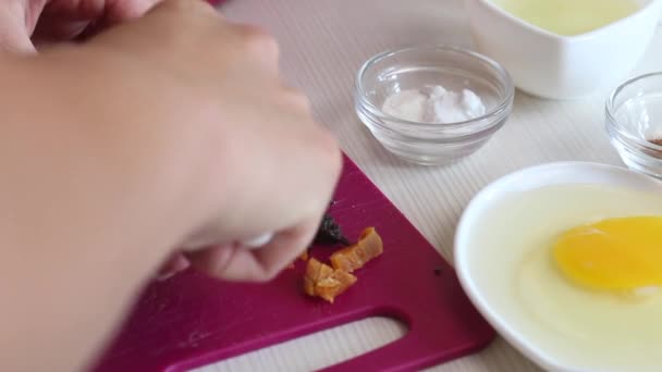 Cooking carrot cake. Woman cuts dried fruits. There are other ingredients nearby. Close-up shot. — Video Stock