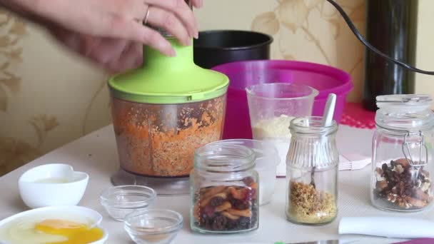 Cooking carrot cake. A woman chops carrots and walnuts in a blender bowl. The ingredients are laid out on the table. Close-up shot — Αρχείο Βίντεο