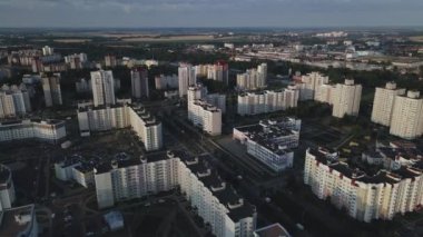 Şafakta şehir üzerinde uçacağız. Doğan güneşin ışınlarında, çok katlı binalar ve yeşil bir alan görülebilir. Hava fotoğrafçılığı.