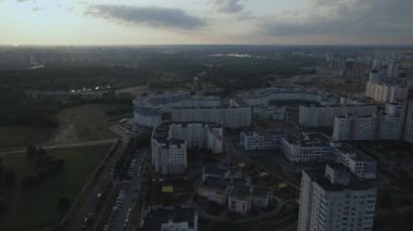 Şafakta şehir üzerinde uçacağız. Doğan güneşin ışınlarında, çok katlı binalar ve yeşil bir alan görülebilir. Hava fotoğrafçılığı.