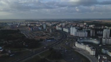 Şafakta şehir üzerinde uçacağız. Doğan güneşin ışınlarında, çok katlı binalar ve yeşil bir alan görülebilir. Hava fotoğrafçılığı.