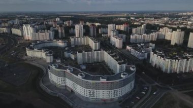 Şafakta şehir üzerinde uçacağız. Doğan güneşin ışınlarında, çok katlı binalar ve yeşil bir alan görülebilir. Hava fotoğrafçılığı.