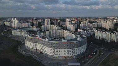 Şafakta şehir üzerinde uçacağız. Doğan güneşin ışınlarında, çok katlı binalar ve yeşil bir alan görülebilir. Hava fotoğrafçılığı.