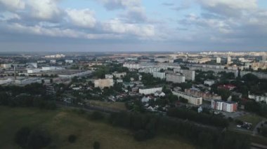Şafakta şehir üzerinde uçacağız. Doğan güneşin ışınlarında, çok katlı binalar ve yeşil bir alan görülebilir. Hava fotoğrafçılığı.