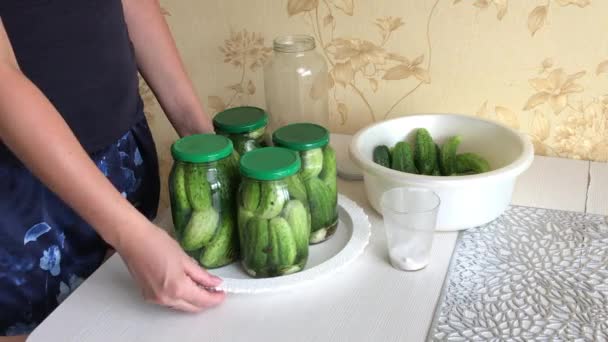 Een vrouw demonstreert potten komkommers. Komkommers zijn bedekt met augurken marinade. Instandhouding van oogsten. — Stockvideo