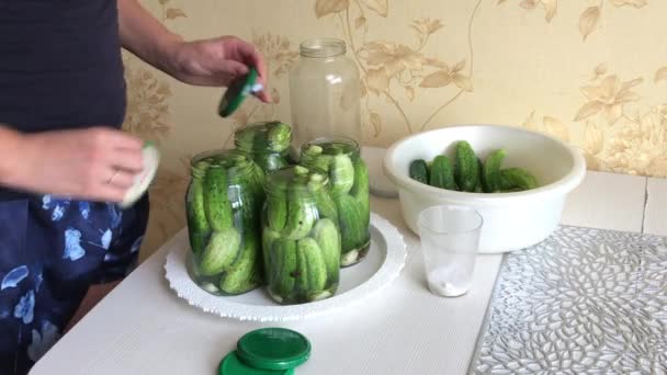 De vrouw sluit het deksel van een pot komkommers. Komkommers zijn bedekt met augurken marinade. Oogstbewaring. Close-up opname. — Stockvideo