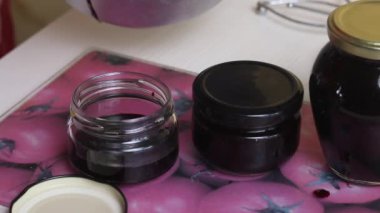 Bir kadın kavanozlara yabanmersini reçeli dolduruyor. Kapağı kapat. Evde yabanmersini reçeli yapıyorum. Yabanmersinlerinin korunması ve hazırlanması. Yakın çekim..