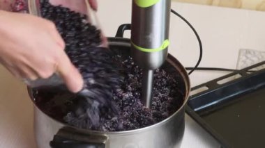 Evde yabanmersini reçeli yapıyorum. Bir kadın yaban mersini ve şekeri püre yapmak için blender kullanır. Yabanmersinlerinin korunması ve hazırlanması. Yakın çekim..
