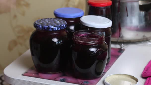 Una mujer cierra un frasco de mermelada de arándanos cocida. Haciendo mermelada de arándanos en casa. Conservación y preparación de arándanos — Vídeos de Stock