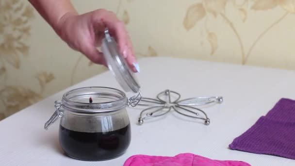 Eine Frau schließt ein Glas mit gekochter Blaubeermarmelade. Heidelbeermarmelade zu Hause zubereiten. Konservierung und Zubereitung von Blaubeeren. — Stockvideo