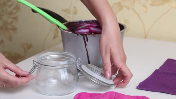 Eine Frau gießt gekochte Blaubeermarmelade in ein Glas. Heidelbeermarmelade zu Hause zubereiten. Konservierung und Zubereitung von Blaubeeren. — Stockvideo