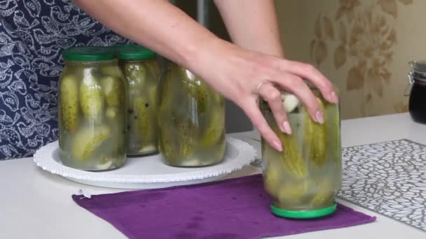 La mujer entrega los frascos de pepinos en escabeche y los coloca con la tapa hacia abajo. Pepinos en vinagre en casa. Conservación de la cosecha vegetal. Primer plano de disparo. — Vídeos de Stock