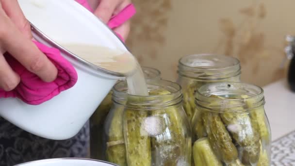 Een vrouw giet kokende marinade over komkommers in potten. Pickling komkommers thuis. Plantaardige oogstbescherming. Close-up opname — Stockvideo