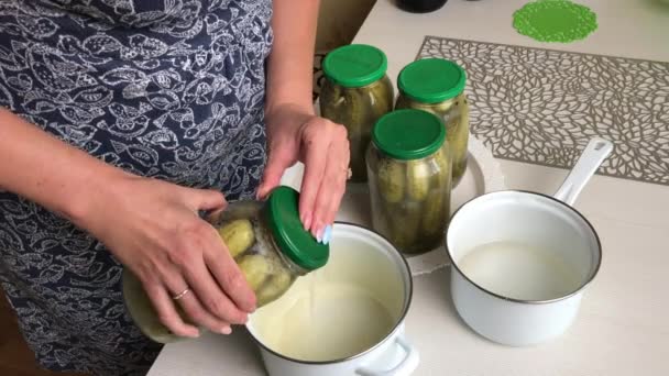 Жінка поливає соломинку для маринування огірків у каструлю. Збирати огірки в домашніх умовах. Збереження врожаю овочів . — стокове відео