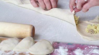 Bir kadın patates püresini rulo hamura sarar. Hamur köftesi hazırlıyor. Yakın çekim..