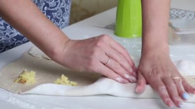 Bir kadın kıyma ve patates püresini rulo hamura sarar. Patatesli hamur tatlısı ve kıyma..