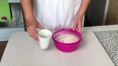 Bir kadın hamur işi için hamur yoğurur. Una ve karışıma su ekler. Patatesli hamur tatlısı ve kıyma..