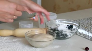 Bir kadın nişasta ile yabanmersinini karıştırıyor. Mangırlı konteynırın yanında. Mantı pişiriyorum..