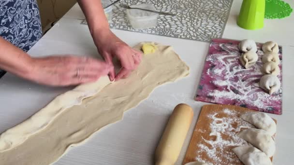 A woman wraps mashed potatoes and minced meat in rolled dough. Cooking dumplings stuffed with mashed potatoes and minced meat — Stock Video