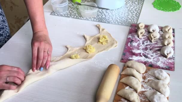 Žena balí bramborovou kaši a mleté maso do rolovaného těsta. Připravuje knedlíky plněné bramborovou kaší a mletým masem. — Stock video