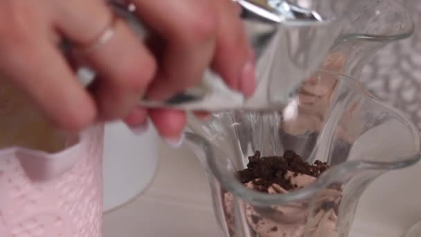 A woman pours biscuit crumbs into a bowl and adds cream from a pastry bag. Makes a dessert with cream and biscuit crumbs. Close-up shot — Stock Video