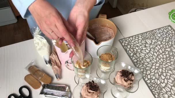 Bir kadın bisküvi kırıntılarını ve kremayı kaselere koyar. Krema ve bisküvi kırıntılarıyla tatlı hazırlar. — Stok video