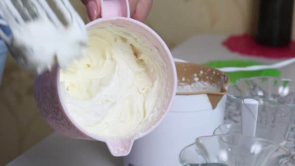 Una donna sta montando la panna con un frullatore. Dimostra il prodotto finito. Prepara la crema per dessert. Dolce con panna e briciole di biscotto. Primo piano.. — Video Stock