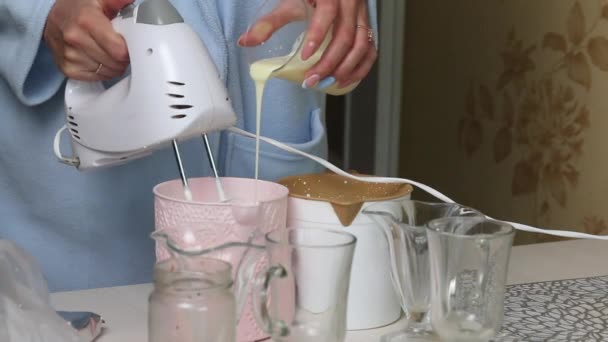 Bir kadın mikserle krema çırpıyor. Aynı zamanda onlara yoğunlaştırılmış süt ekliyor. Tatlı için krema hazırlıyor. Kremalı ve bisküvili tatlı.. — Stok video