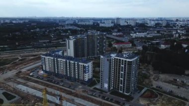 Modern bir şehir bloğunun inşaatı. Çok katlı binalar ve şehir altyapısının unsurları. İnşaat işleri ve binaların inşaatı devam ediyor. Gün batımında hava fotoğrafçılığı.